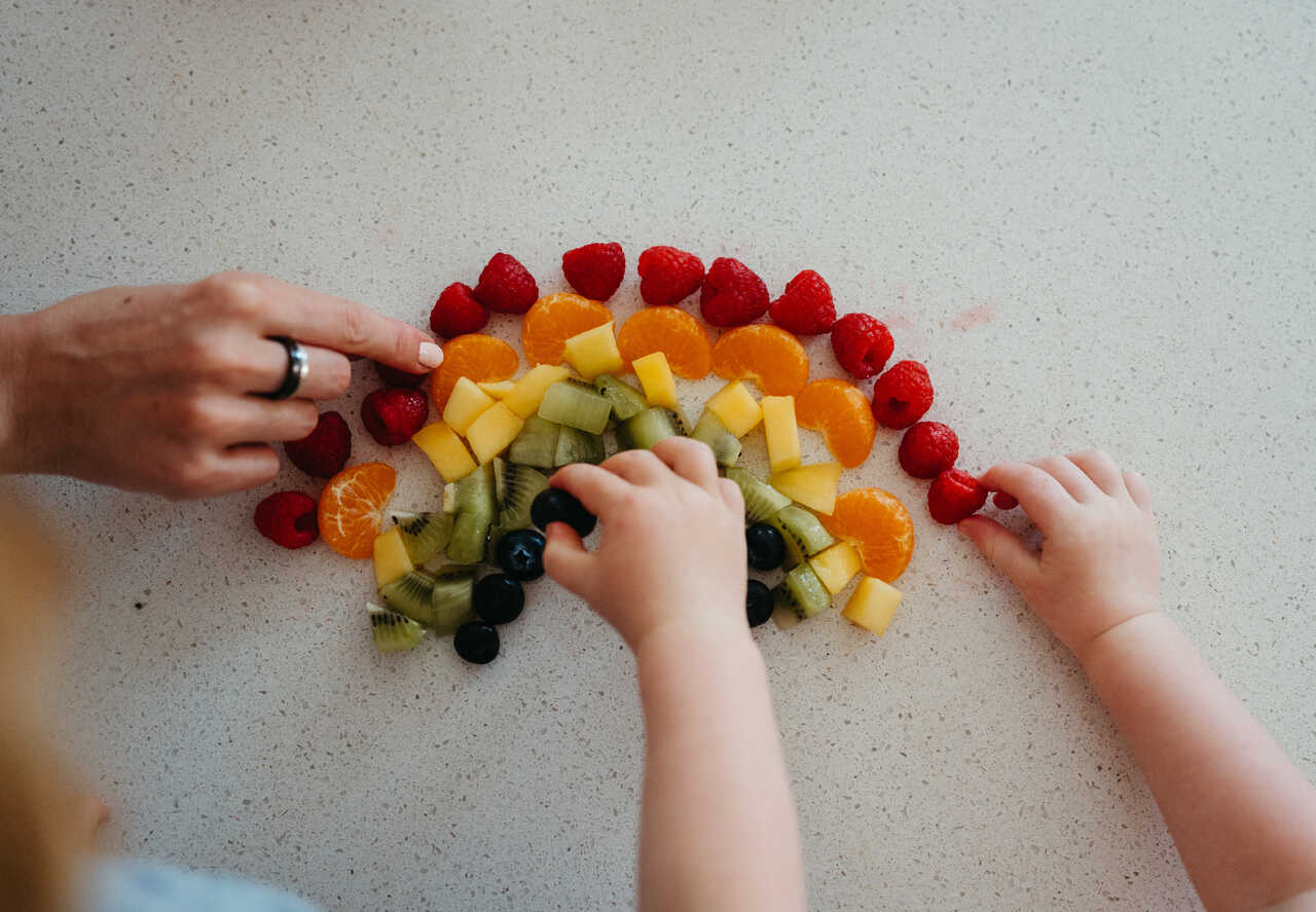 Raspberries, mandarins, mango, kiwi, and blueberries create a fruit rainbow