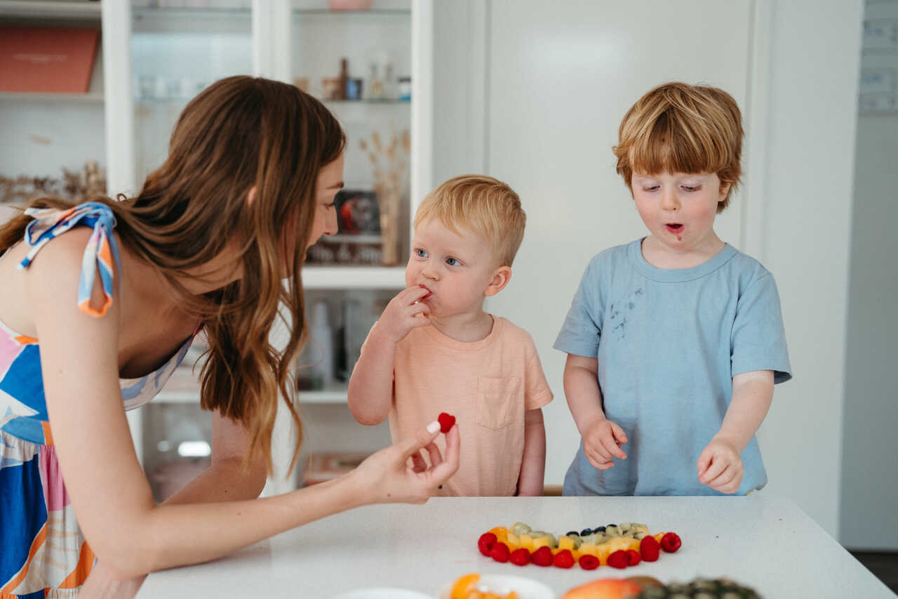 Children exploring fruit eat raspberries