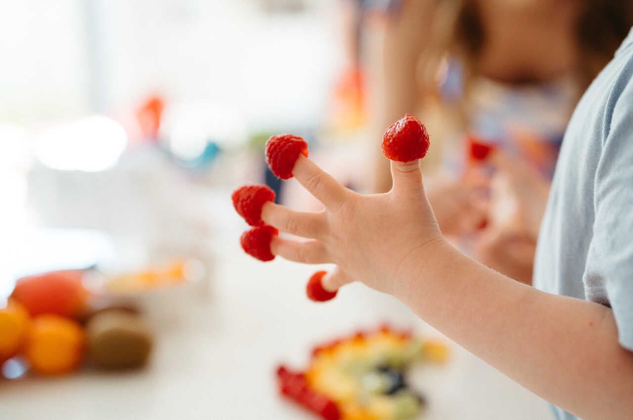 Raspberries on the tips of a childs fingers